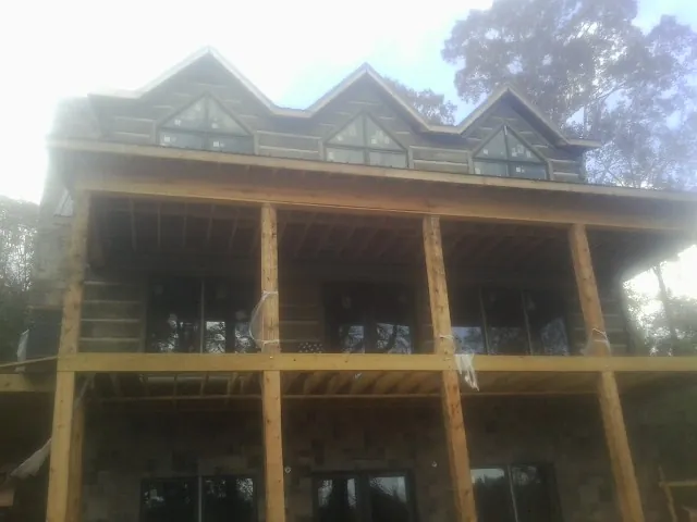 Dormers and porch framing on a large log home under construction — Roof Coating work by our crew in Coventry